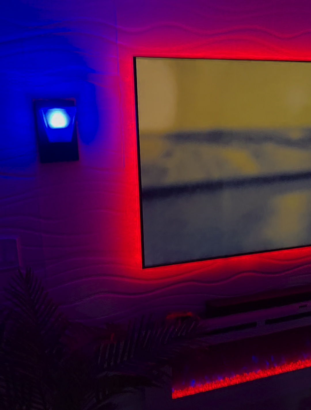 Close-up of a mounted TV with red backlight and a smart plug-in night light