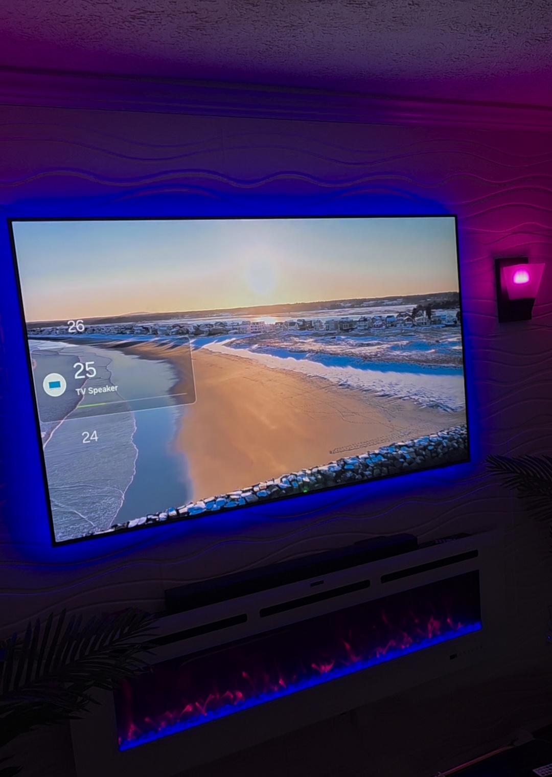 Wall-mounted TV with blue backlighting above a linear electric fireplace