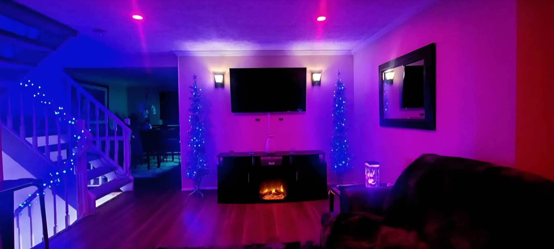Living room with color-changing LED accent lighting, mounted TV, and wall sconces