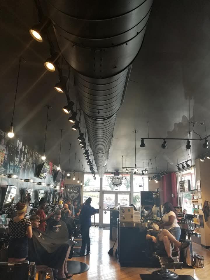 Barbershop interior with black track lighting and pendant fixtures along the ceiling