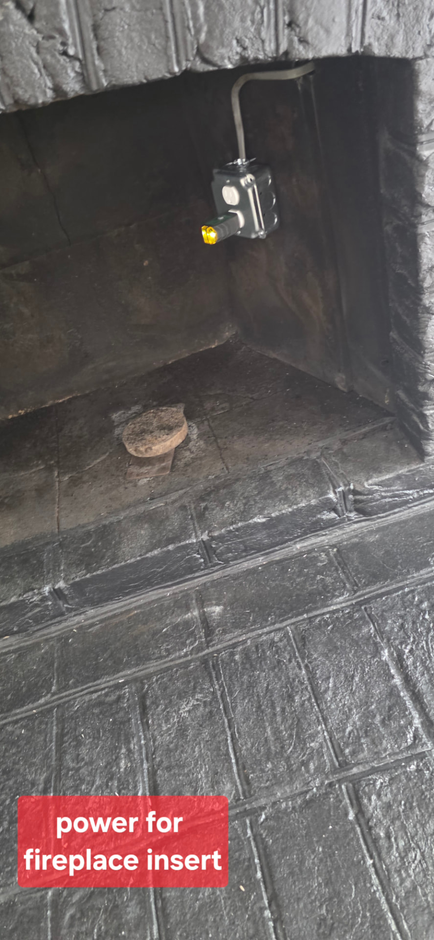 Metal junction box with outlet wired inside a masonry fireplace to power an electric fireplace insert