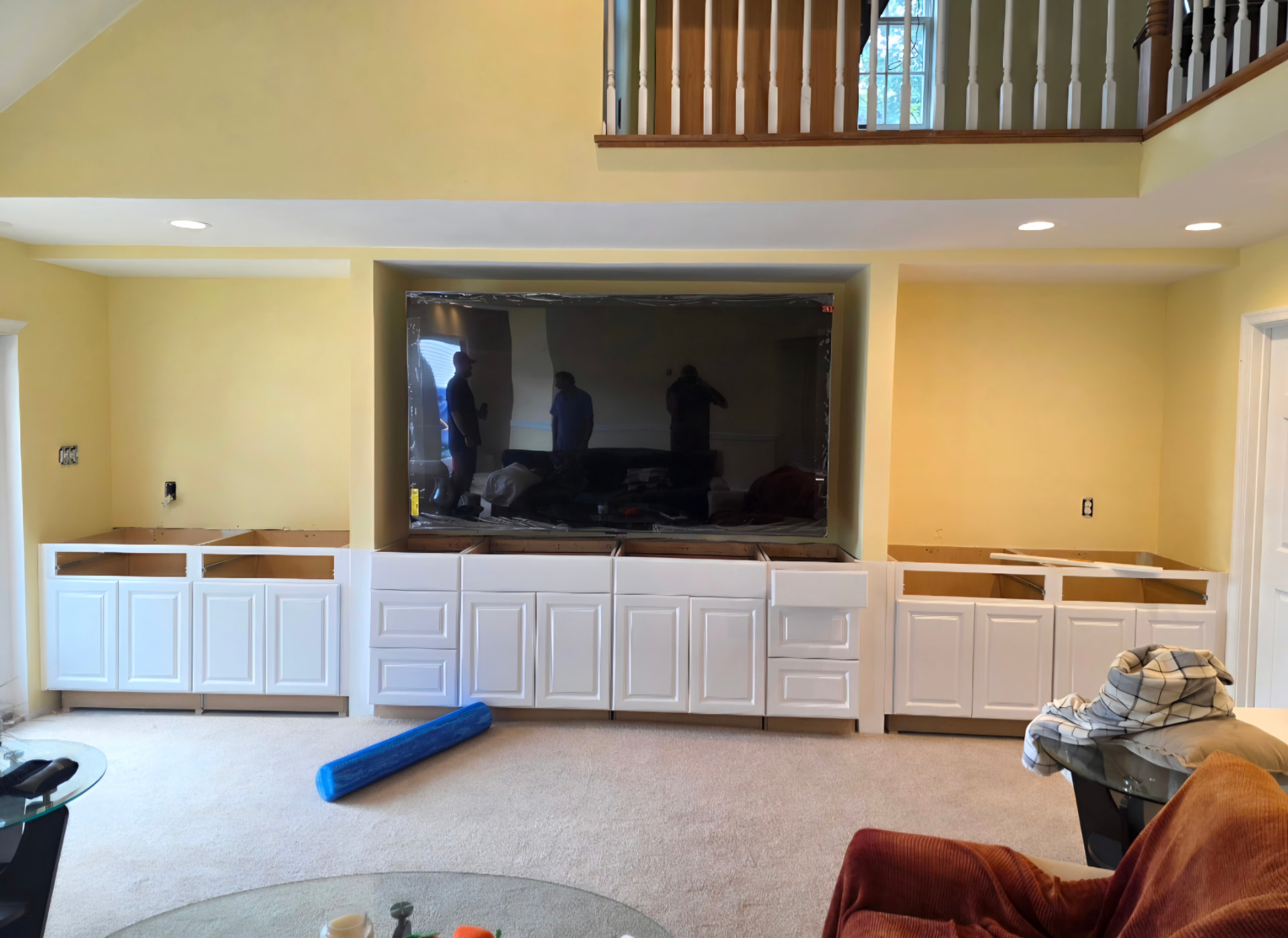 Large recessed TV framed by white built-in cabinetry with recessed ceiling lights