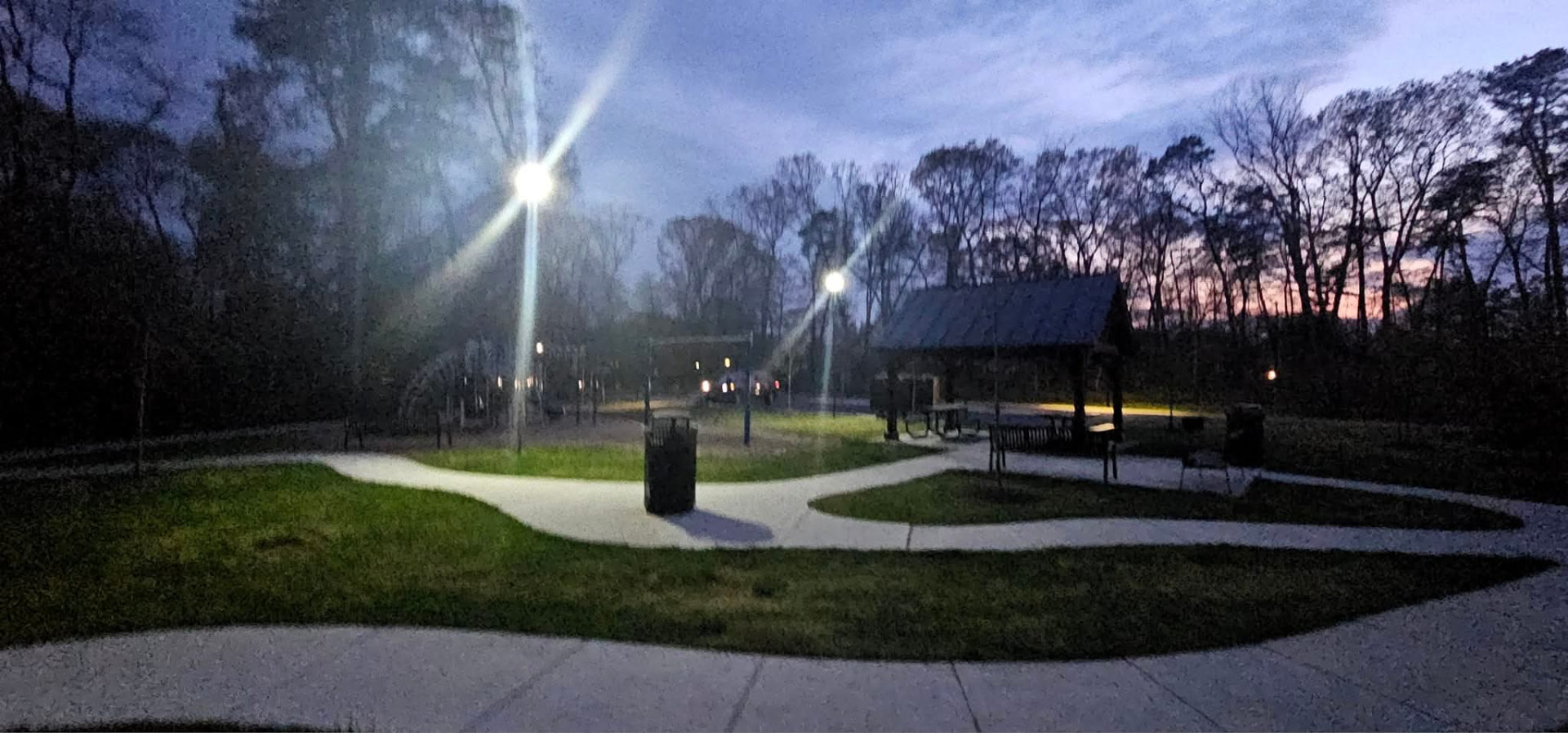 Park walking paths and pavilion lit by two solar LED pole lights at dusk