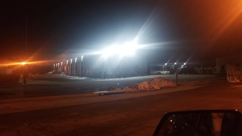 Warehouse exterior lit at night by bright LED wall packs and area lighting